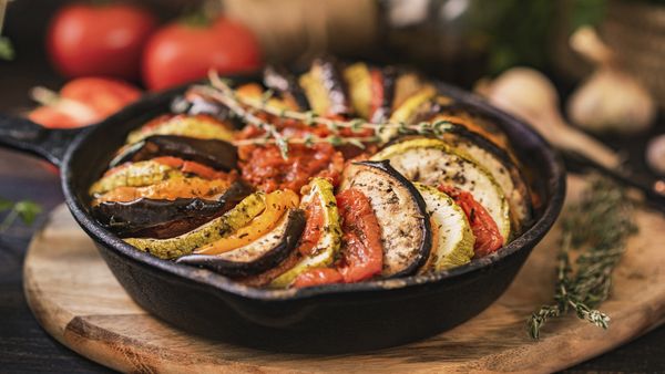 Ratatouille, made of zucchini, eggplants, peppers, onions, garlic and tomatoes slices with aromatic herbs, bread. 