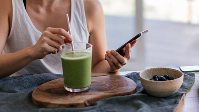 Woman drinking a smoothie on her phone