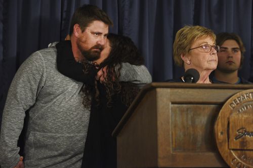 Ronald Johnson's children Toni and Jesse hug as their mother addresses the media.