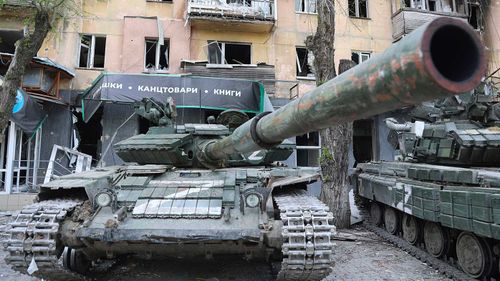 Tanks of Donetsk People's Republic militia stand next to a damaged apartment building in Mariupol.