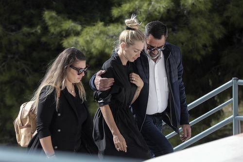 Red-eyed widow Viktoria has to be helped up the steps to the funeral service of her murdered husband.
