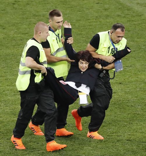 A woman who invaded the pitch is carried out by security guards during the World Cup final between France and Croatia at Luzhniki Stadium in Moscow on July 15, 2018. Russian protest group and musical act Pussy Riot has claimed responsibility for the incident. (Kyodo via AP Images)