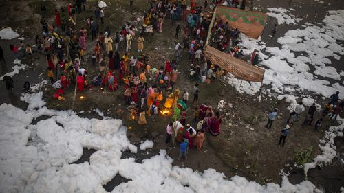 Indian Hindu devotees perform rituals on the banks of Yamuna river, covered by chemical foam caused due to industrial and domestic pollution, during Chhath Puja festival in New Delhi, India, Wednesday, Nov. 10, 2021. A vast stretch of one of India's most sacred rivers, the Yamuna, is covered with toxic foam, caused partly by high pollutants discharged from industries ringing the capital New Delhi. Still, hundreds of Hindu devotees Wednesday stood knee-deep in its frothy, toxic waters, sometimes 