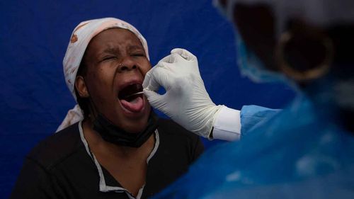 A throat swab is taken from a patient to test for COVID-19 at a facility in Soweto, South Africa.