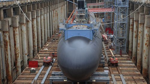FILE- Shipyard workers at General Dynamics Electric Boat in Groton, Conn., prepare a submarine for float-off, July 30, 2015. (AP Photo/Jessica Hill, File)