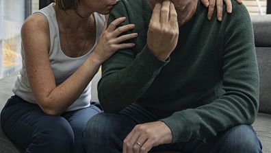 Sad couple sitting on bed.