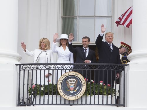 First ladies Brigette Macron and Melania Trump join their husbands as they wave to the crowd. (AAP)
