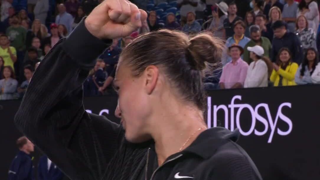 Aryna Sabalenka kisses her biceps during her on-court interview.