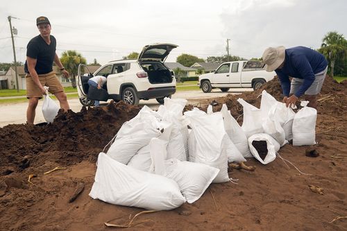 2023 年 8 月 29 日星期二，圣约翰县居民在佛罗里达州新月海滩填沙袋，为飓风阿达利亚的到来做准备。