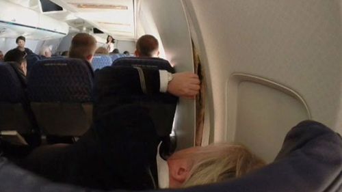 A passenger posted this photo to Facebook of a crew member inspecting the cracked cabin wall. 