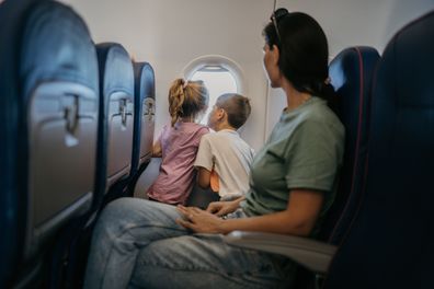 Mother with two children, son and daughter travel by plane, children look through the window