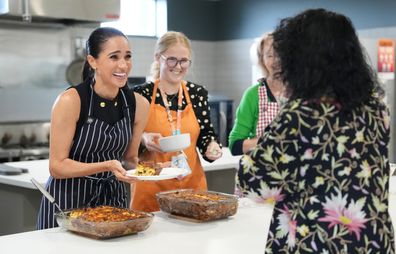Meghan, Duchess of Sussex and staff from McAuley Community Services for Women, a homeless and family violence shelter for women, serve lunch to a resident in the Footscray suburb of Melbourne, Australia, on April 14, 2026. Meghan and Prince Harry, Duke of Sussex, are on a four-day visit to Australia, with appearances in Melbourne, Canberra and Sydney. (Photo by Jonathan Brady-Pool/Getty Images)