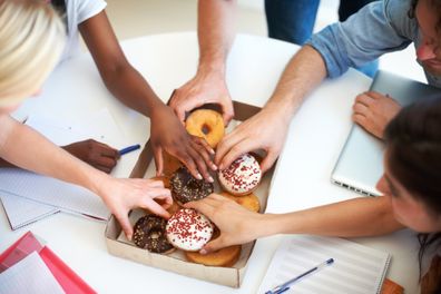 Coworkers reaching for a tasty snack during a brainstorming session