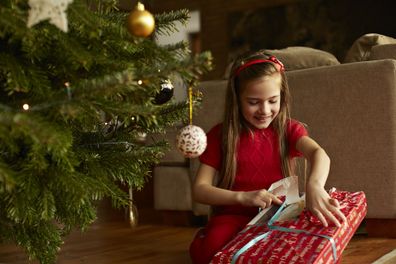 Child unwrapping Christmas gift