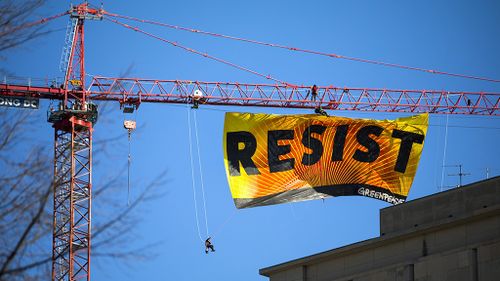 Greenpeace activists have hung a huge banner from a crane as an anti-Trump protest. (AAP)