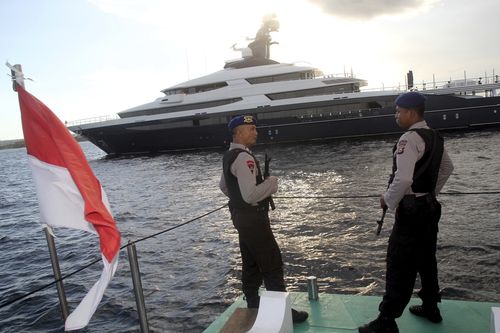 Indonesian police officers stand guard as the luxury yacht 'Equanimity' is seen in the background off Bali island, Indonesia, Wednesday, Feb. 28, 2018. Indonesia has seized the yacht that is wanted by U.S. authorities as part of a probe into alleged multibillion-dollar corruption at Malaysian state investment fund 1MBD. (AP Photo/Yoan Ari)