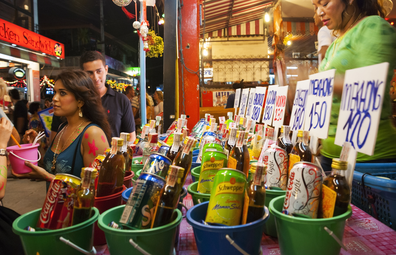 Haad Rin, Ko Phangan, Thailand - August 29, 2007: A Thai woman sells buckets of soft drinks and liquor to visitors celebrating the monthly Full Moon Party in Haad Rin, a beach destination on the island of Ko Phangan, Thailand