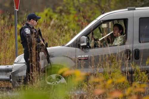 Police officers stop to question a driver at a roadblock, Thursday, Oct. 26, 2023, in Lisbon, Maine, 