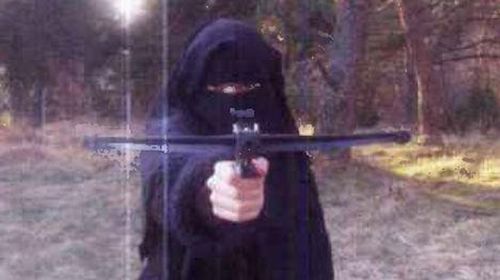 Hayat Bomeddiene aims a small crossbow directly at the camera in a chilling photo that emerged earlier today as police announced they were searching for her. (Le Monde)