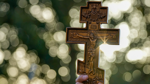 A crucifix is held aloft as Serbian priests hold a service for Novak Djokovic and his supporters outside the Park Hotel, used as an immigration detention hotel where Djokovic is confined in Melbourne, Australia, Sunday, Jan. 9, 2022.