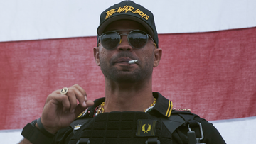 Proud Boys leader Enrique Tarrio wears a hat that says The War Boys and smokes a cigarette at a rally in Delta Park on Saturday, Sept. 26, 2020, in Portland, Ore. (AP Photo/Allison Dinner)