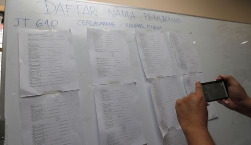 A man takes photo of the list of passengers of Lion Air flight JT610 at Soekarno-Hatta International Airport in Tangerang.