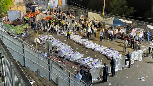 Israeli security officials and rescuers stand around the bodies of victims who died during a Lag Ba'Omer celebrations at Mt Meron in northern Israel.