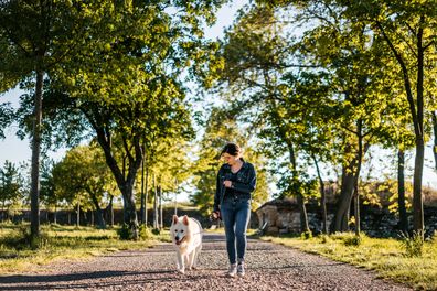 Woman and shepherd dog walking together in public park