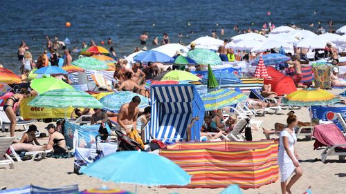 People enjoy the warm temperatures and bright sunshine as they crowd a beach in the Baltic Sea resort of Miedzyzdroje, northwestern Poland. (AAP)