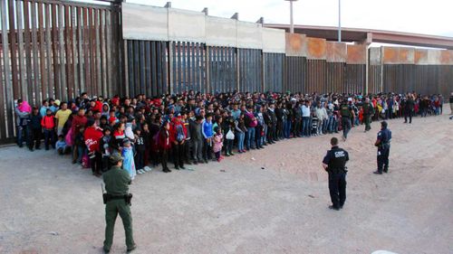 A group of migrants are gathered together after they crossed the border into the USA.