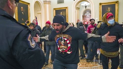 FILE - In this Jan. 6, 2021 file photo, Trump supporters, including Douglas Jensen, center, confront U.S. Capitol Police in the hallway outside the Senate Chambers on Capitol Hill in Washington. An Iowa construction worker and QAnon follower was sentenced Friday, Dec. 16, 2022, to five years in prison for his role in the Jan. 6, 2021 riot.