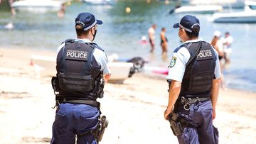 Police at Clareville Beach in northern Sydney ensure crowd limits fall within guidelines for coronavirus restrictions in the city.