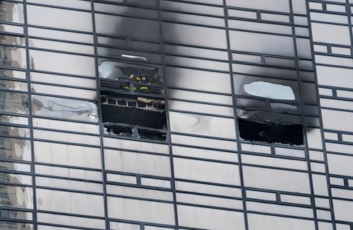 Firefighters look out from the window of a fire damaged apartment in Trump Tower in New York on Saturday, April 7, 2018. (AAP)