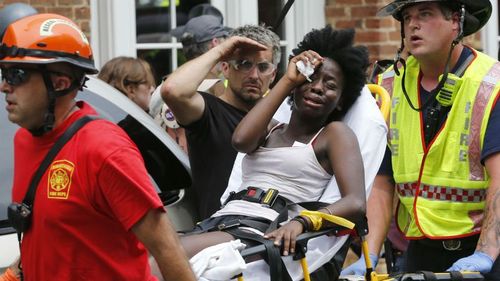 Rescue personnel help an injured woman after a car ran into a large group of protesters after an white nationalist rally in Charlottesville on Saturday. (AP)
