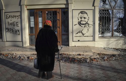 Пожилая женщина смотрит на граффити с изображением командующего ВСУ генерала Валерия Залонного и пишет "С нами Бог и командир Залоньи" На месте ожесточенных боев с русскими оккупантами в Бахмуте, Украина, вторник, 20 декабря 2022 г.