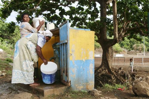 Women fill up buckets with water in the district of M'tsamoudou, near Bandrele, on Mayotte