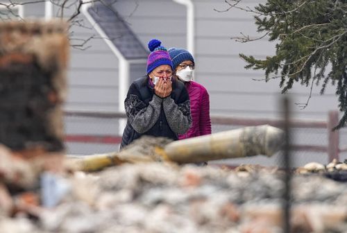 A woman cries as he sees the burned remains of a home destroyed by the Marshall Wildfire in Louisville.
