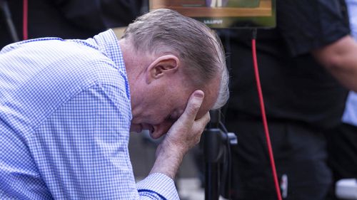 A man listens to the Pell sentencing outside court.