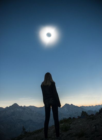 A woman watching an eclipse in the USA, Idaho at Sawtooth Range.