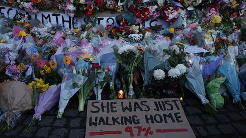 A sign saying "SHE WAS JUST WALKING HOME 97%" is seen among the flowers and candles on Clapham Common where floral tributes have been placed for Sarah Everard in London.