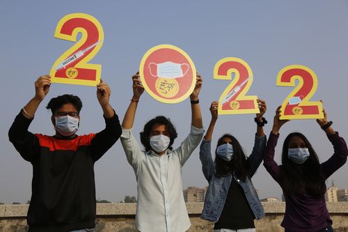 Indians, wearing face masks to help curb the spread of the coronavirus, hold the cutouts to welcome 2022 on New Years Eve in Ahmedabad, India, Friday, Dec. 31, 2021. (AP Photo/Ajit Solanki)