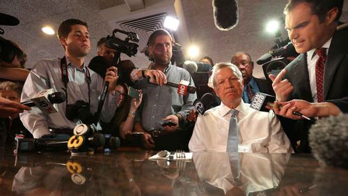 John Kasich (seated) is surrounded by the press at a diner in Philadelphia. (AAP)