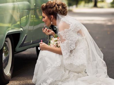 Bride putting on makeup in car reflection