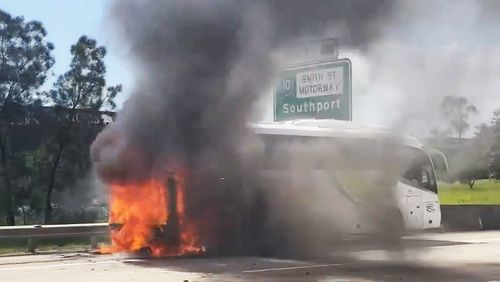 Dozens of children have escaped a bus which burst into flames and sent smoke billowing across a Queensland motorway.