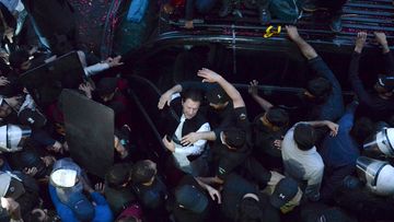 Security personnel make way for former Prime Minister Imran Khan as he arrives to appear in court, in Lahore