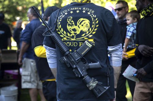 A man carrying a gun is seen during a memorial for Aaron J. Danielson.