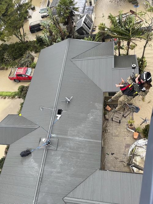 In this image released by the New Zealand Defense Force on Wednesday, Feb. 15, 2023, a child is winched from a rooftop of a home to safety by helicopter in the Esk Valley, near Napier, New Zealand. 