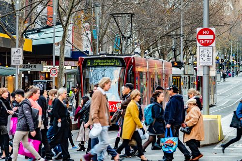 Melbourne, Victoria, Australia, July 14 2018: Five Public Transport Victoria trams are on Swanston Street while pedestrians cross the road at the intersection of Bourke Street.