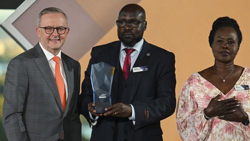 Australian Prime Minister Anthony Albanese presents the Young Australian of the Year winner to  Awer Mabil's mother Agot Dau Atem and his uncle Michael Matiop.