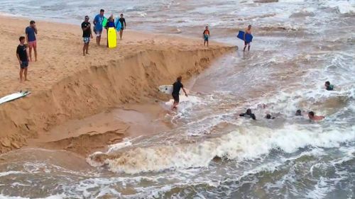 A group of Dee Why surfers have been hailed "heroes" after saving a man being swept out to sea during the city's wild weather.
